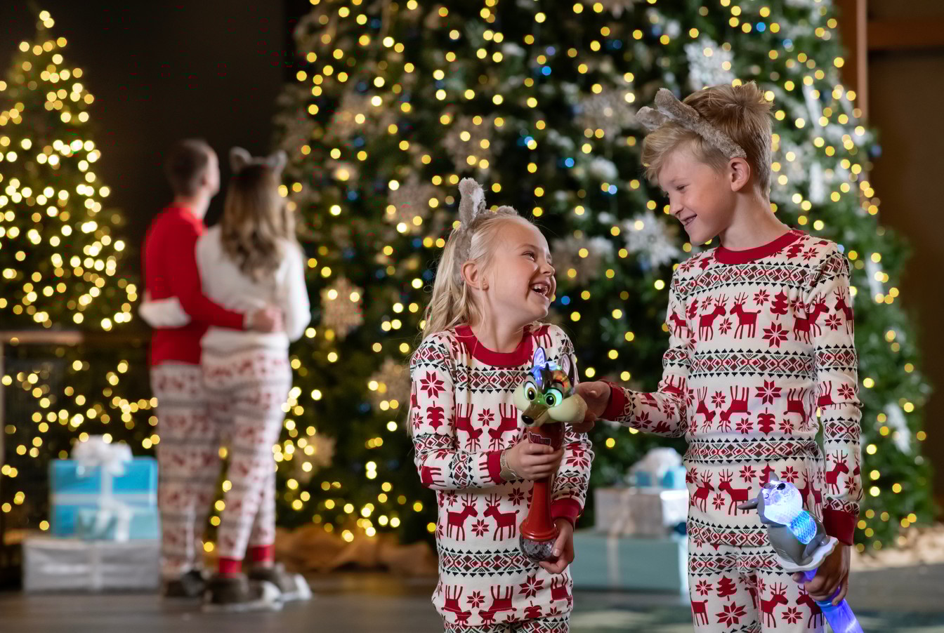 family standing in front of a christmas tree wearing holiday themed PJ's