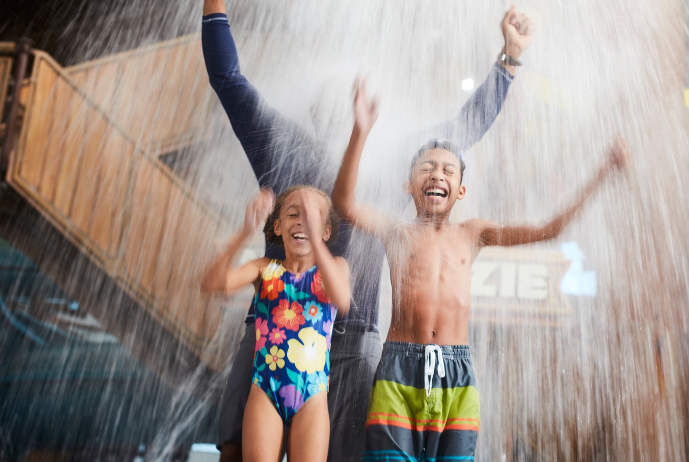 family standing under the water bucket splashing water