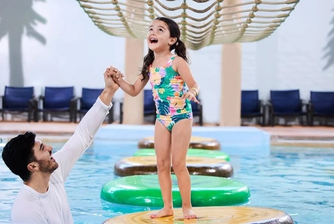 father helping daughters cross the water pool using floating pods 