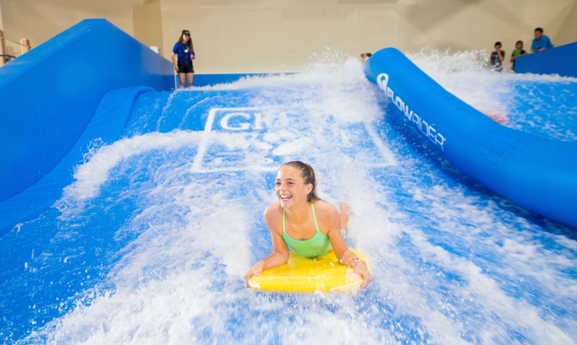 A child rides on a yellow boogie board in the water attraction 