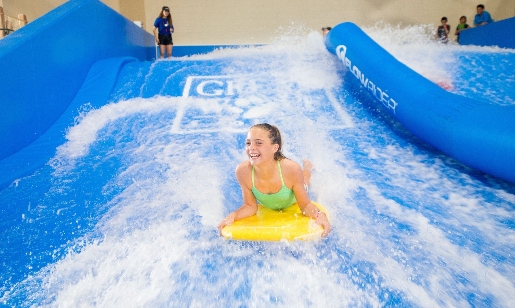 A child rides on a yellow boogie board in the water attraction