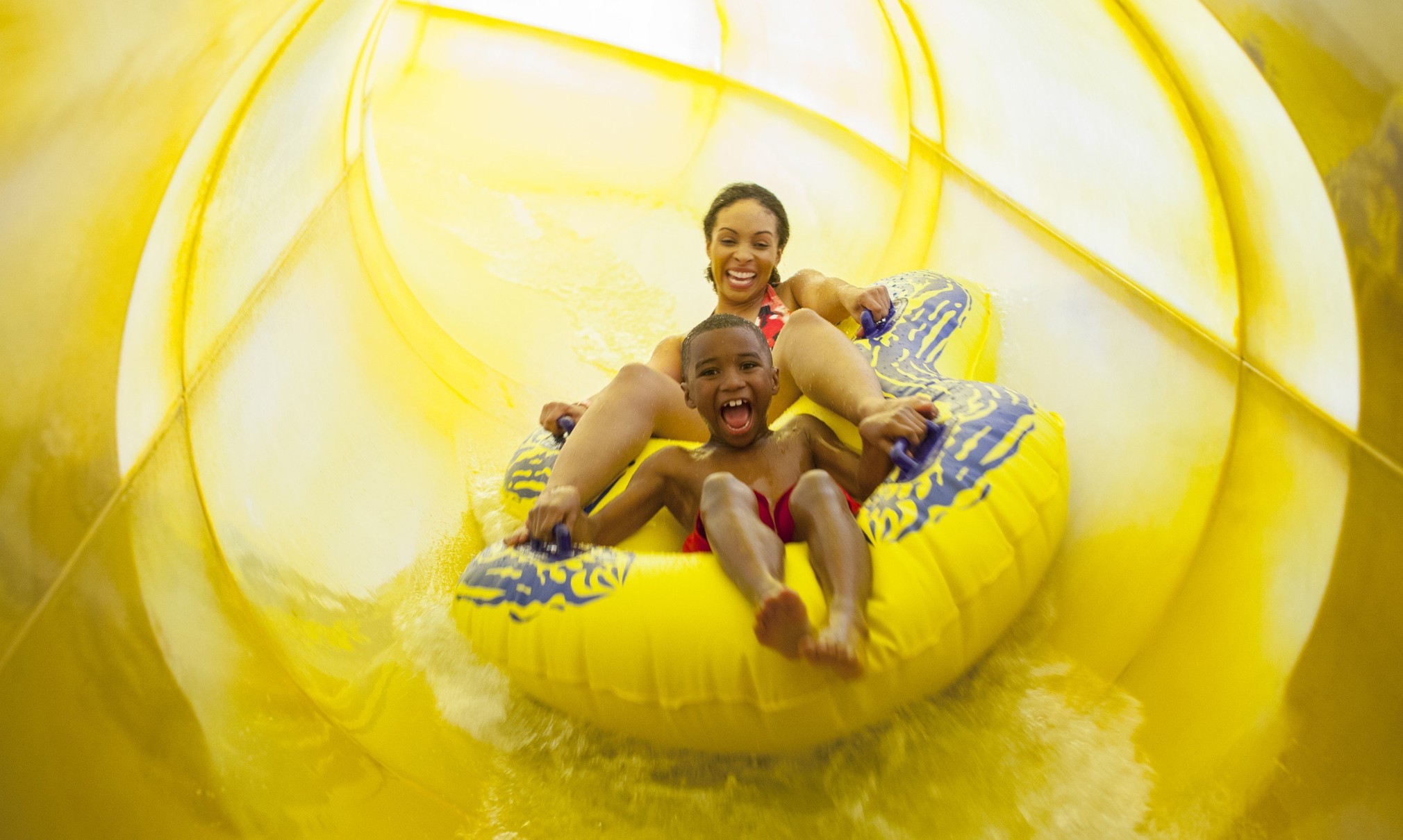 Mother and son in a tube racing down a yellow waterslide