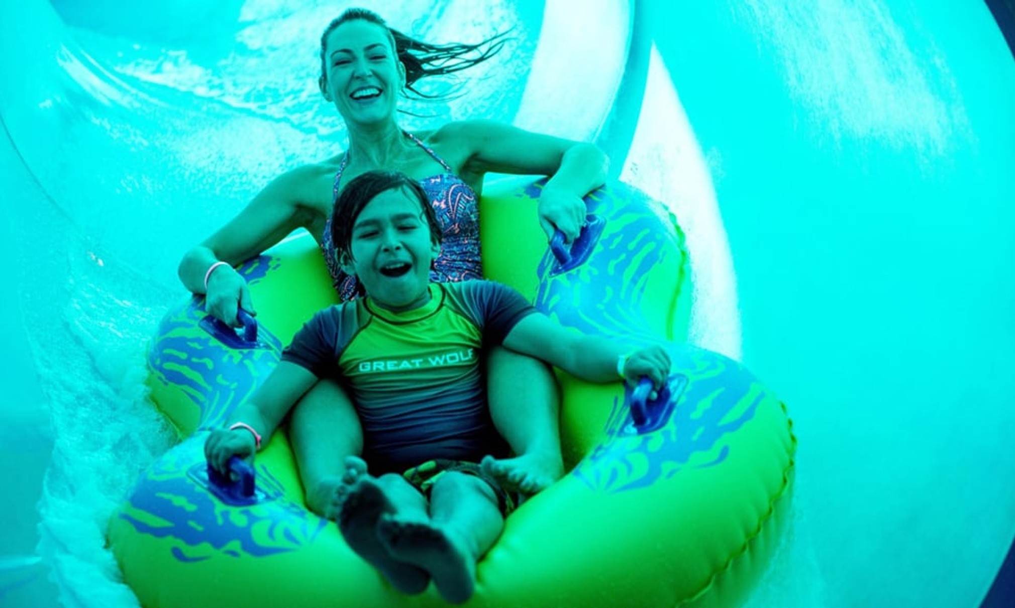 Mother and son in a tube racing down a yellow waterslide 