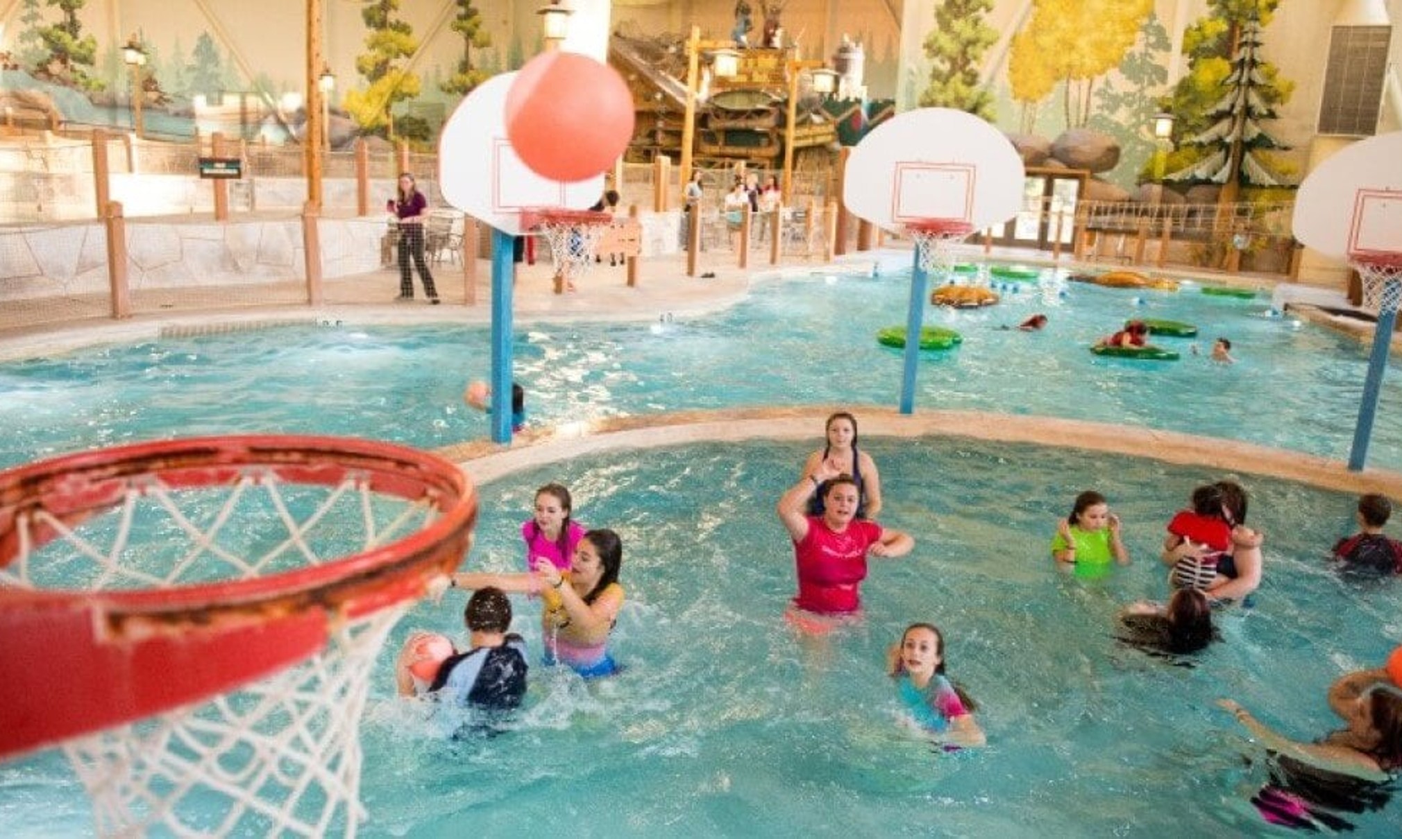 family playing basketball in indoor pool 