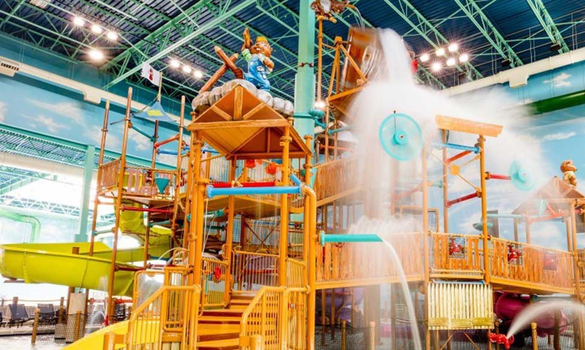 A wide shot of the  water treehouse as water splashes down from a bucket above the jungle gym