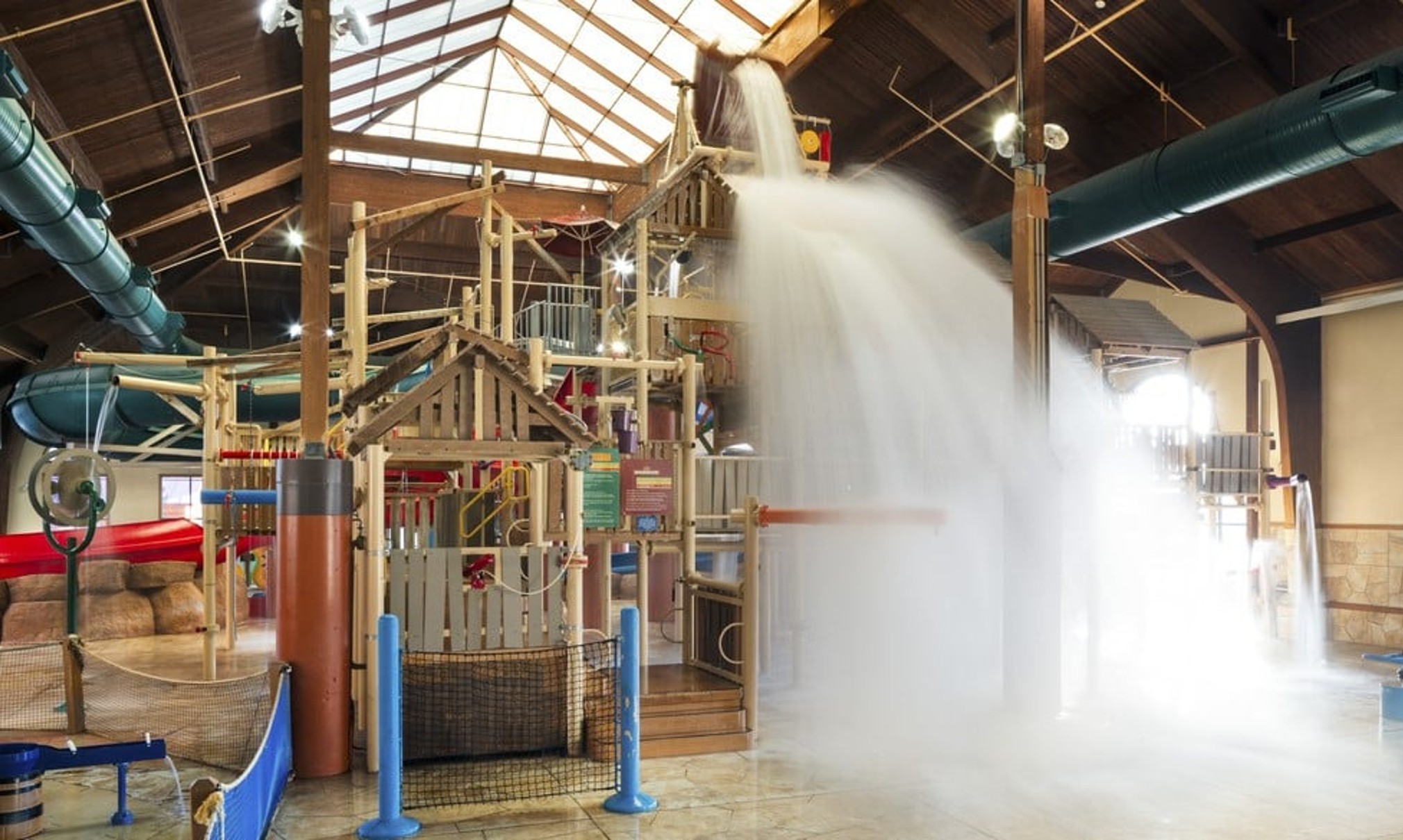 A wide shot of the  water treehouse as water splashes down from a bucket above the jungle gym