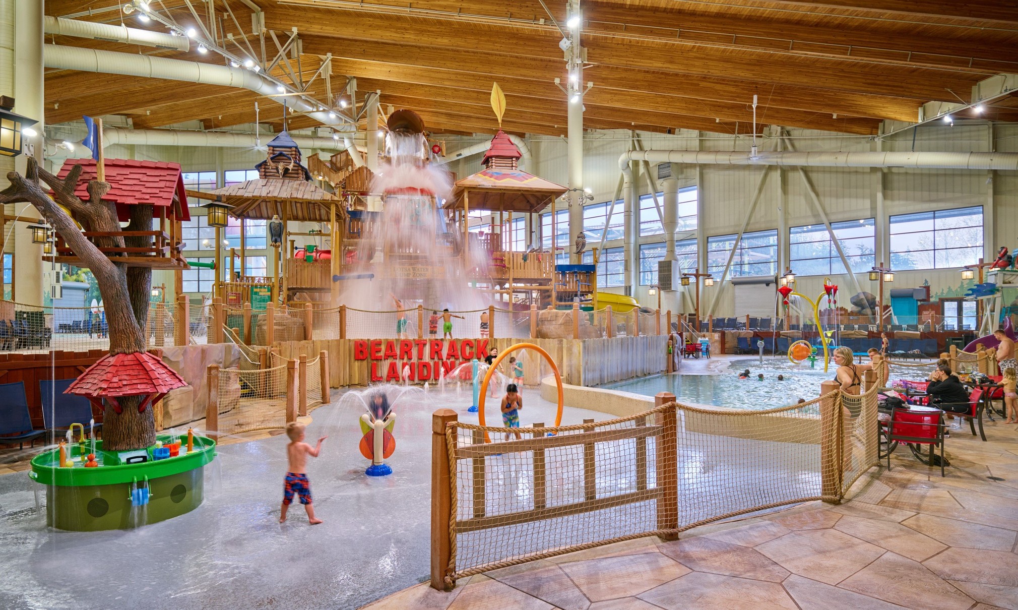 A wide shot of the  water treehouse as water splashes down from a bucket above the jungle gym