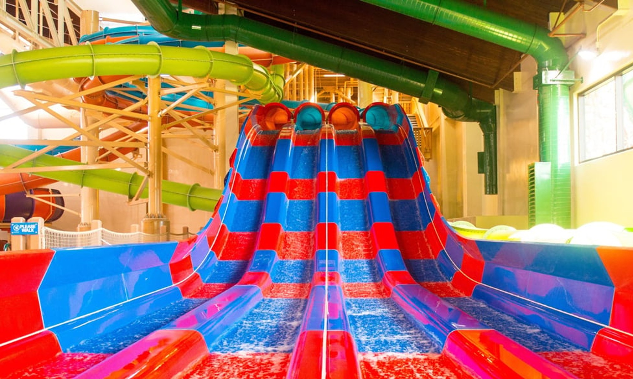 Two kids race down a waterslide laying on their stomaches 
