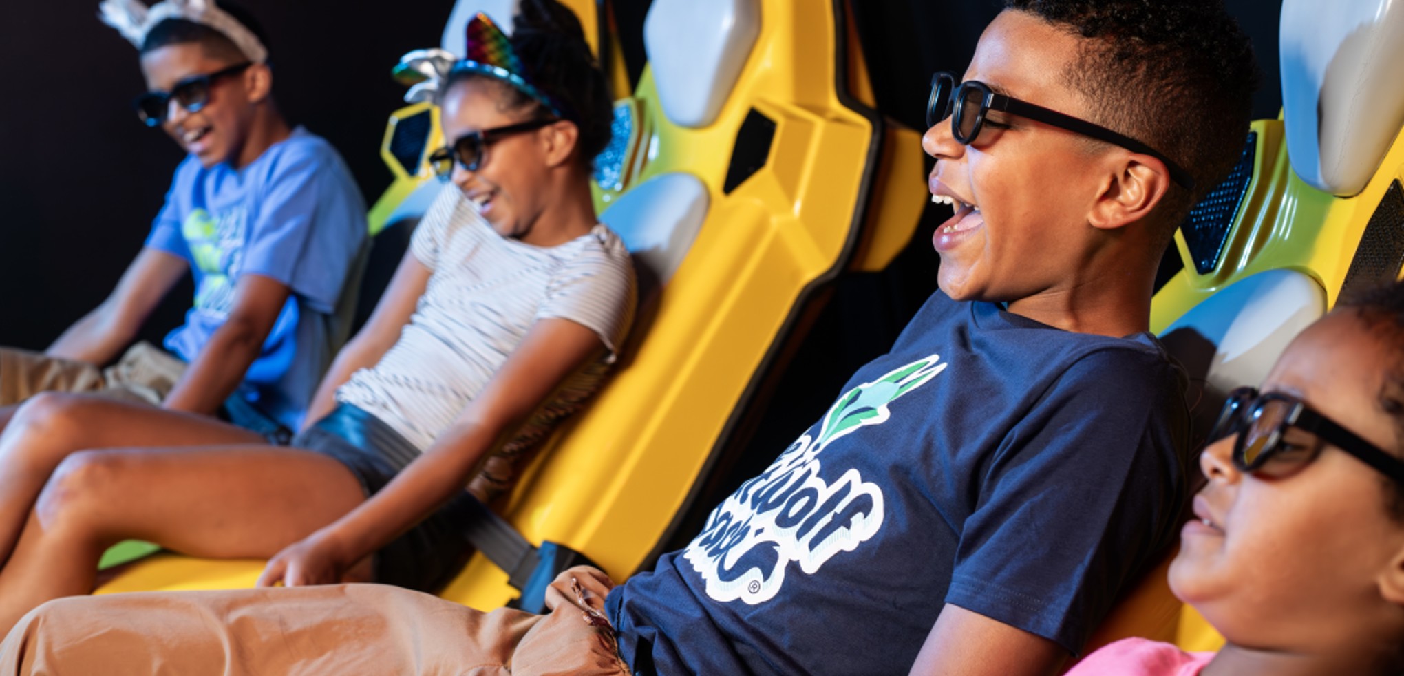 A family of four wear 3D glasses inside the Howly Wood XD Theater at Great Wolf Lodge indoor water park and resort.