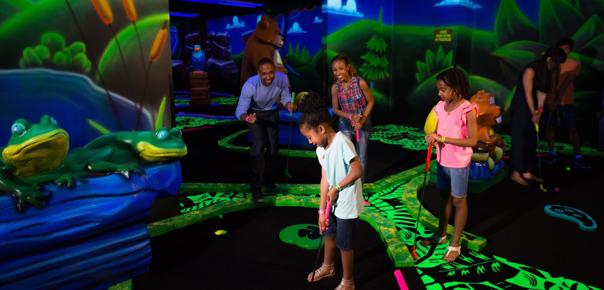 Family watching son play a hole of Glow Golf