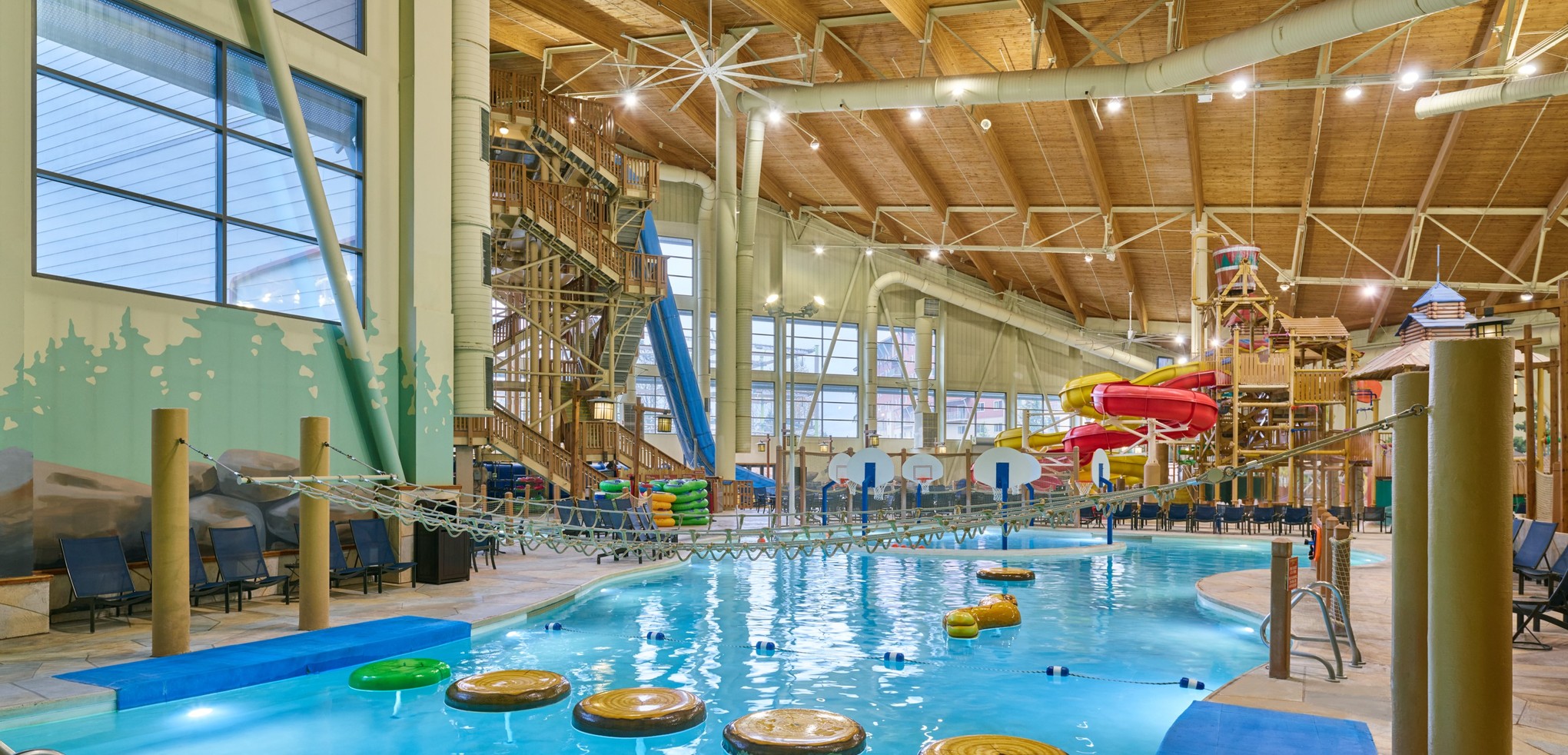 A girl balances on a lily pad float in indoor pool