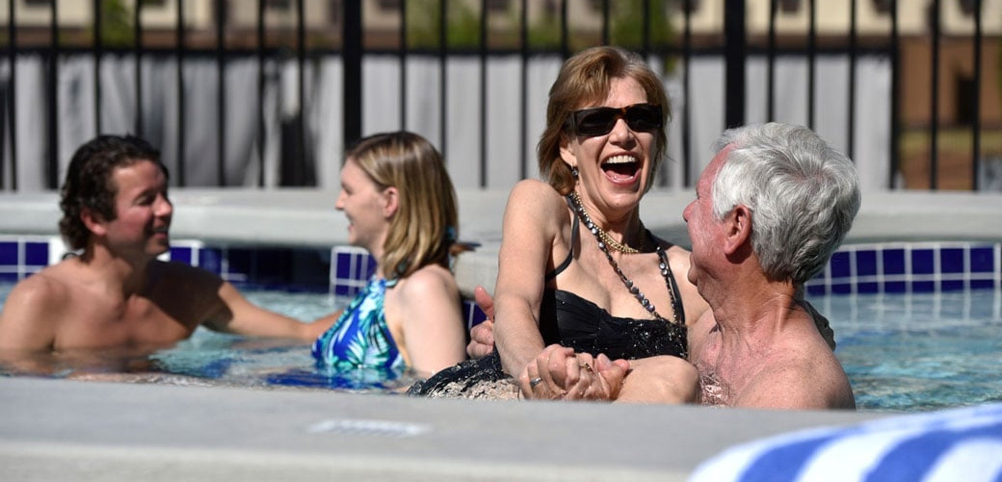 A couple relax in and on the side of the indoor pool 