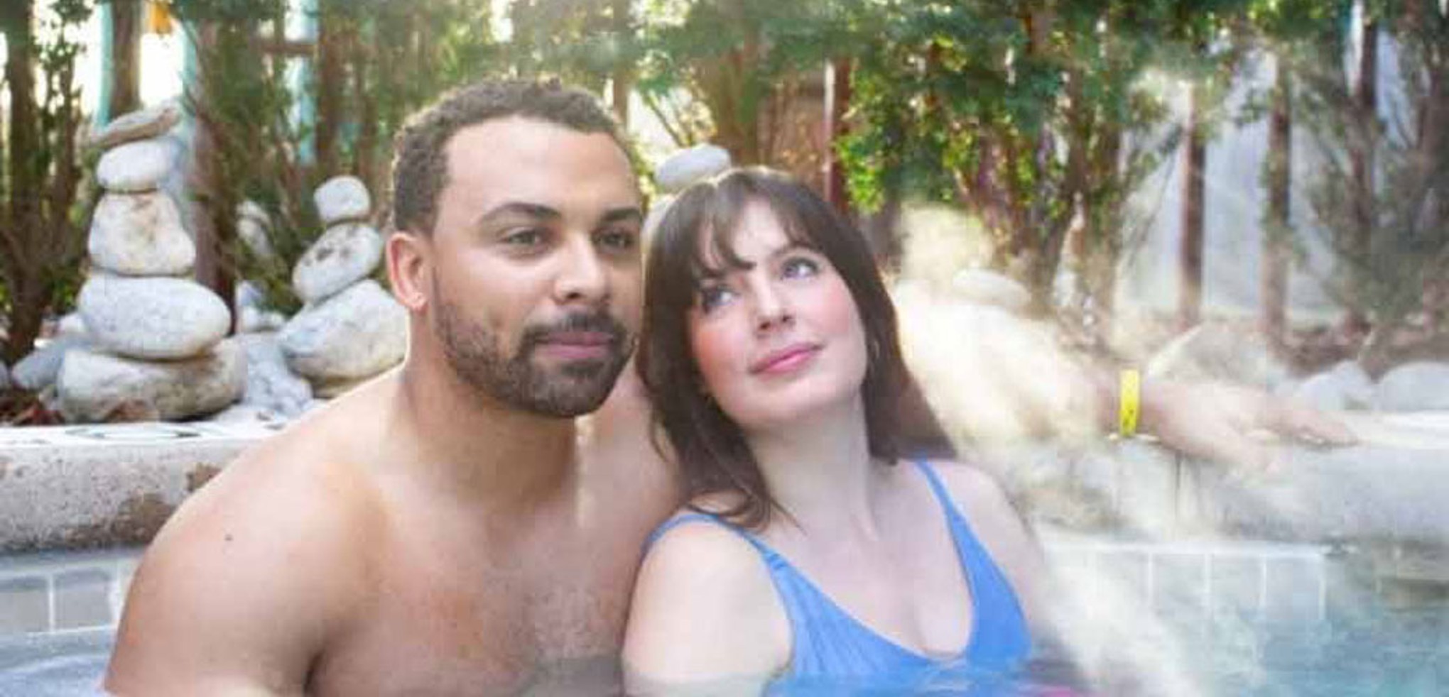 A couple relax by the outdoor whirlpool spa at Great Wolf Lodge indoor water park and resort.