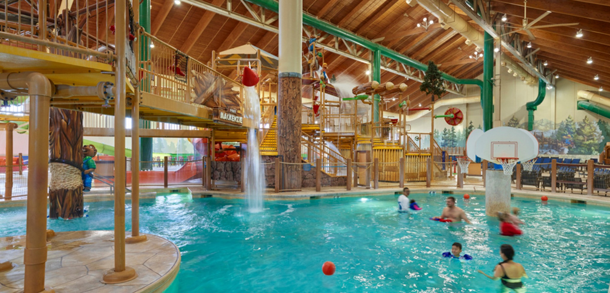 family playing basketball in indoor pool 