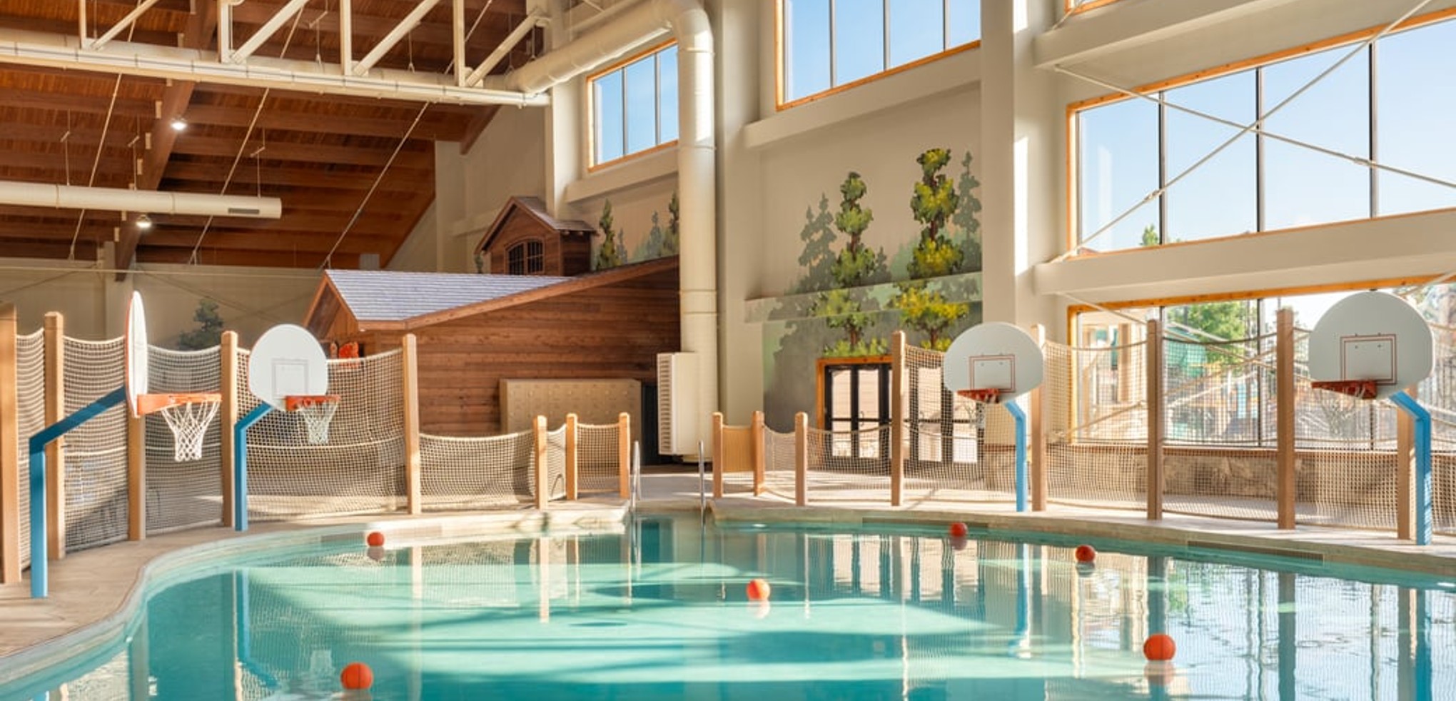 family playing basketball in indoor pool 