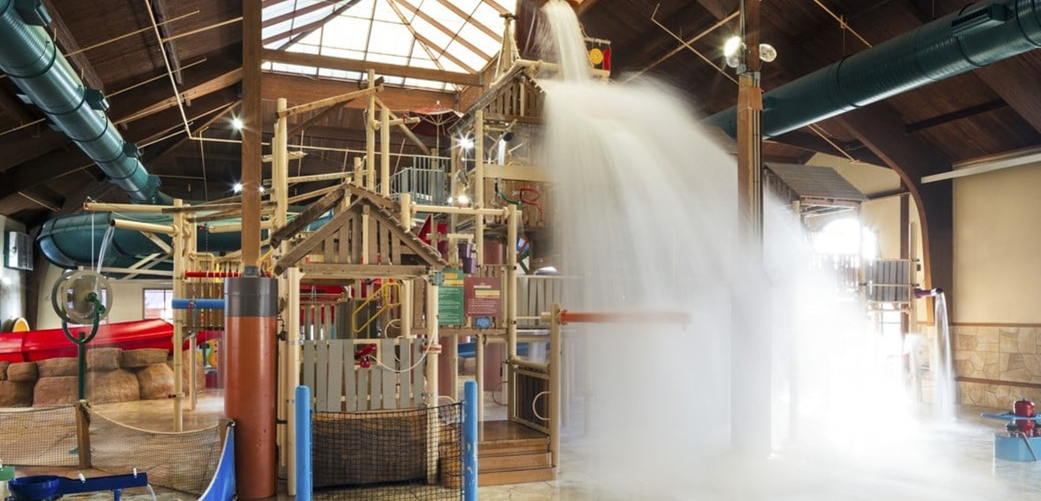 A wide shot of the  water treehouse as water splashes down from a bucket above the jungle gym