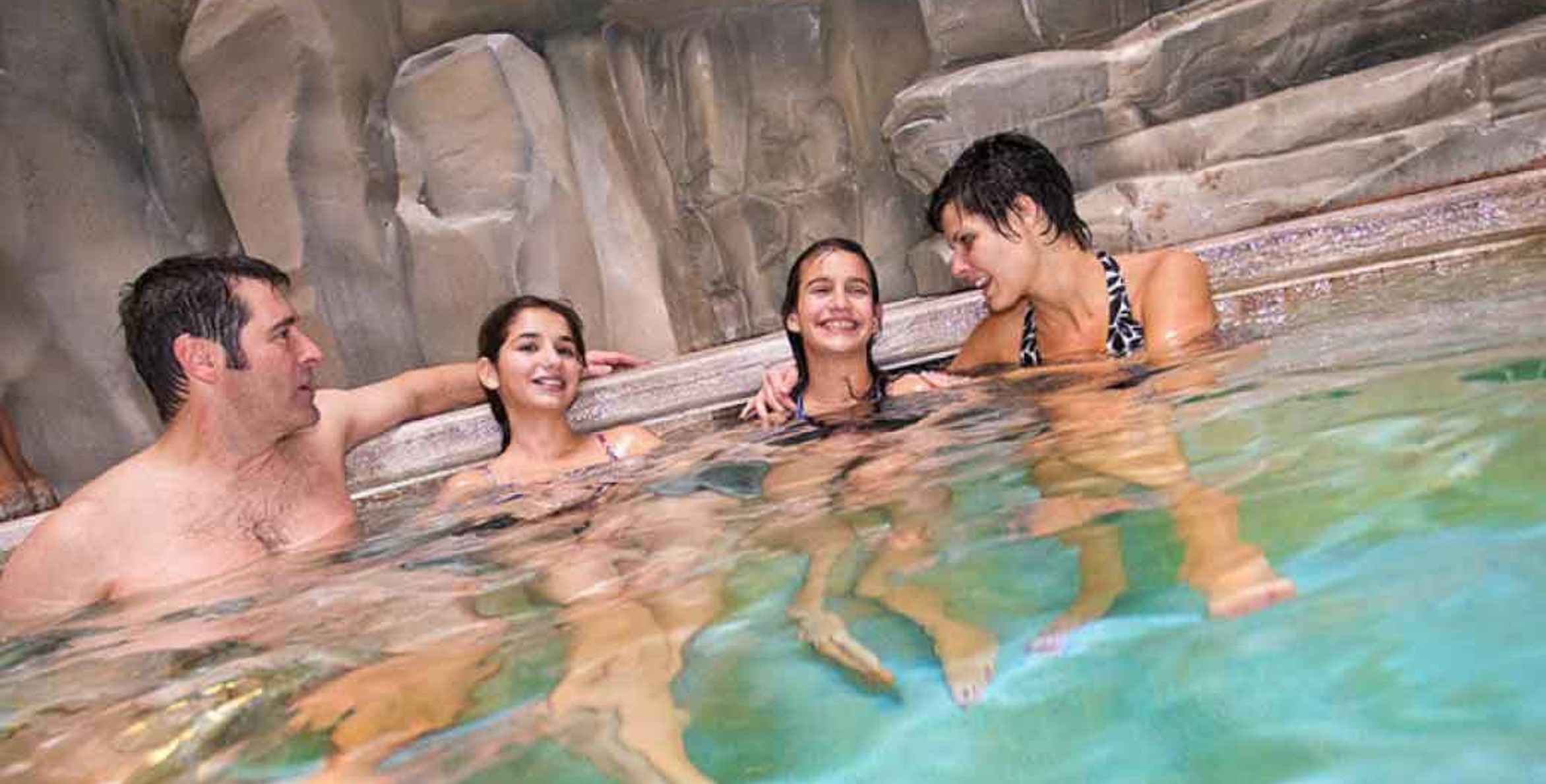 A family of four relaxes in the indoor pool