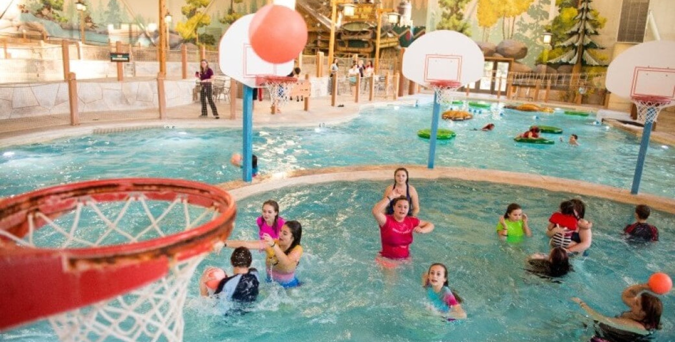 family playing basketball in indoor pool 