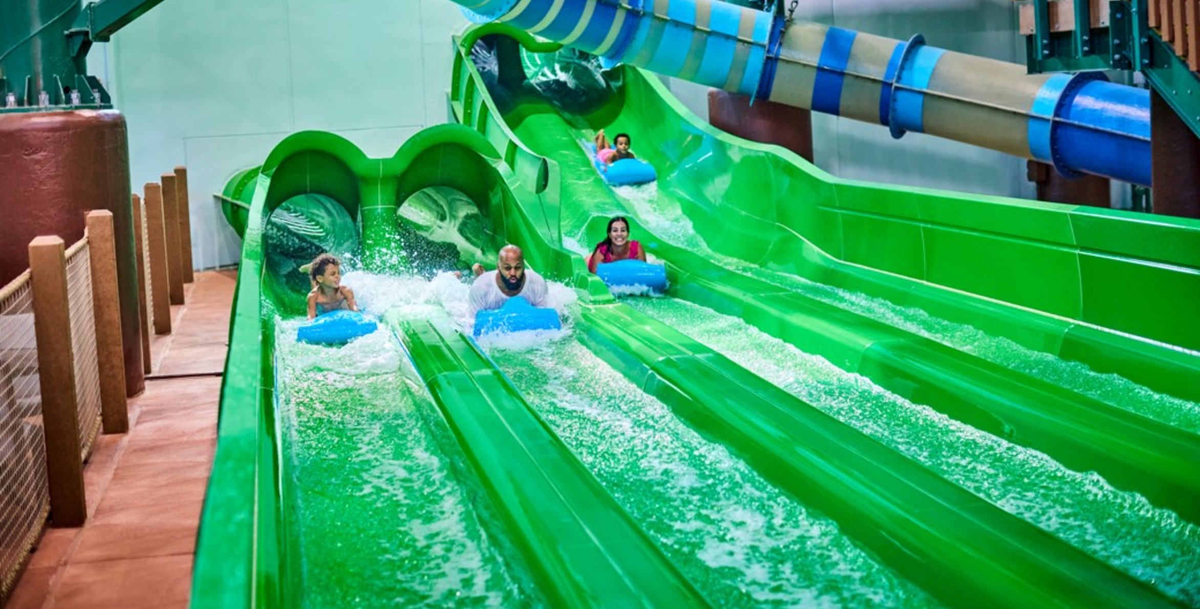 Guests race down a waterslide laying on their stomaches 