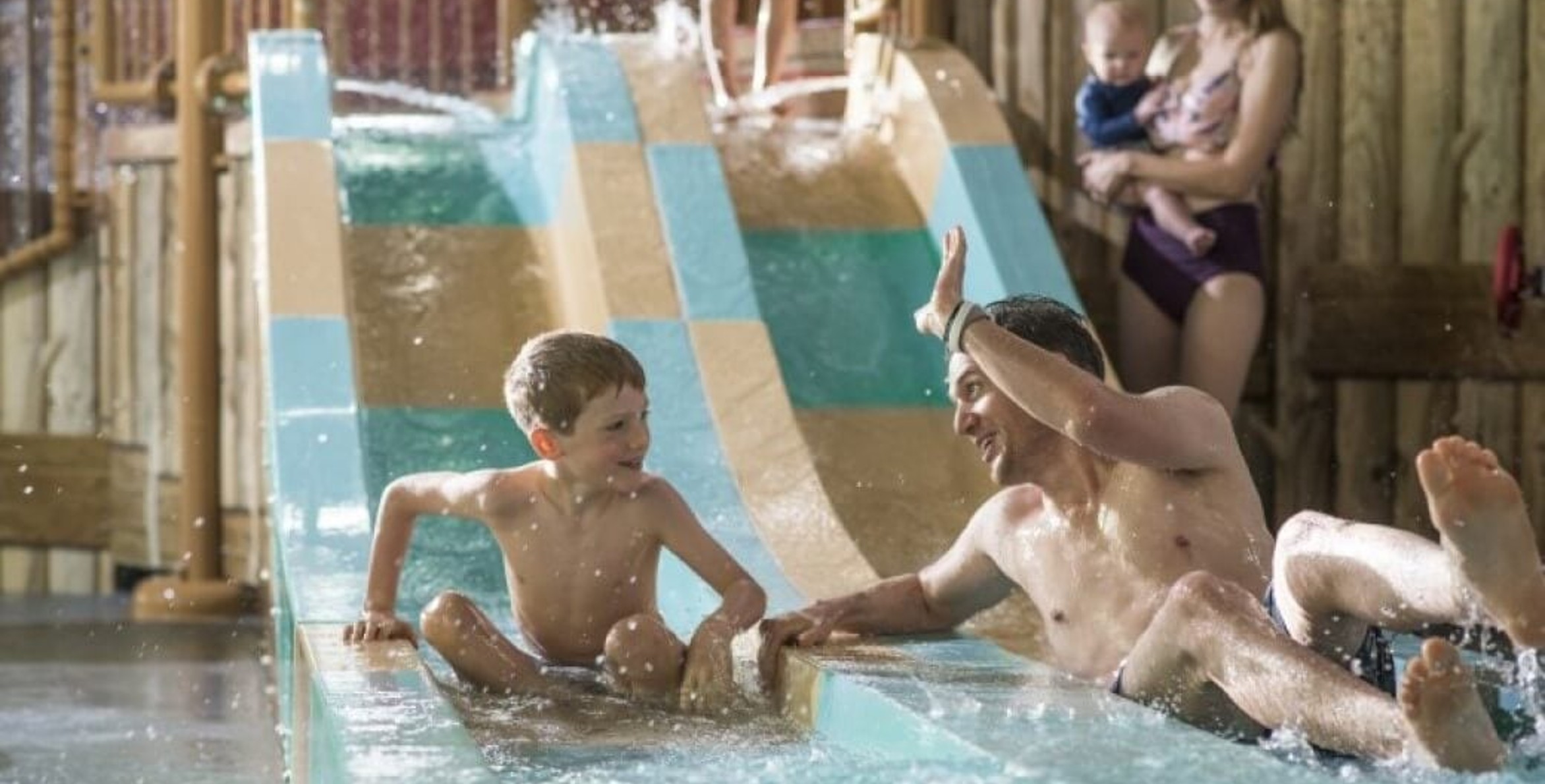 dad high fives his son as they come down a waterslide 