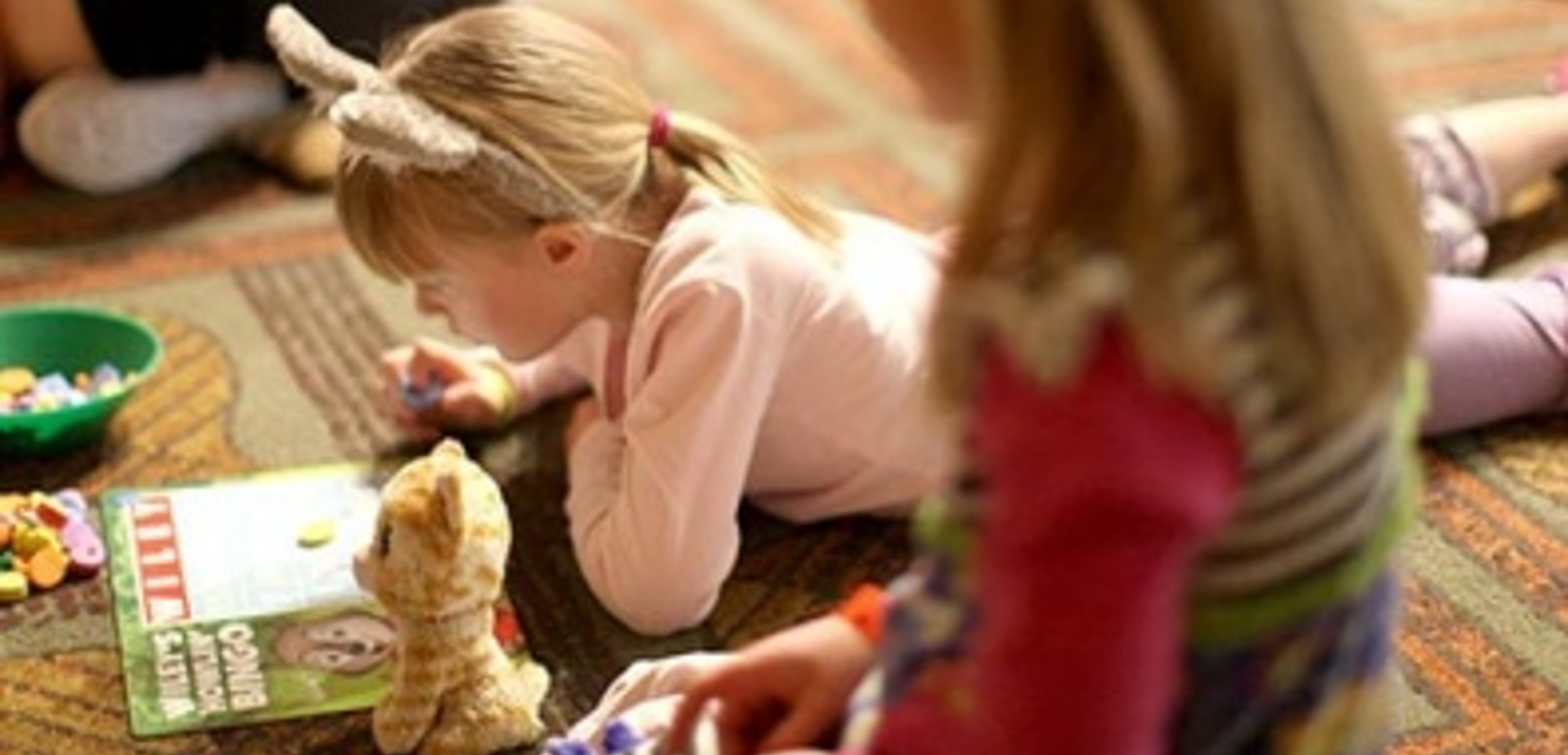 A girl lies on the ground with a coloring book at Great Wolf Lodge indoor water park and resorts.