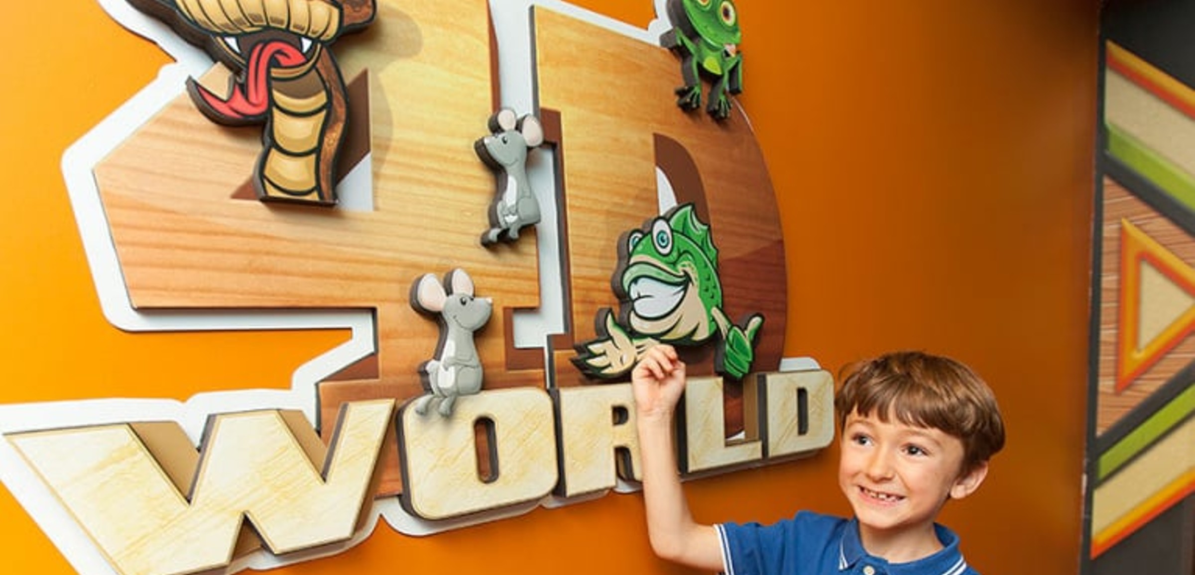 A boy smiles next to the 4D World logo at Great Wolf Lodge indoor water park and resort.
