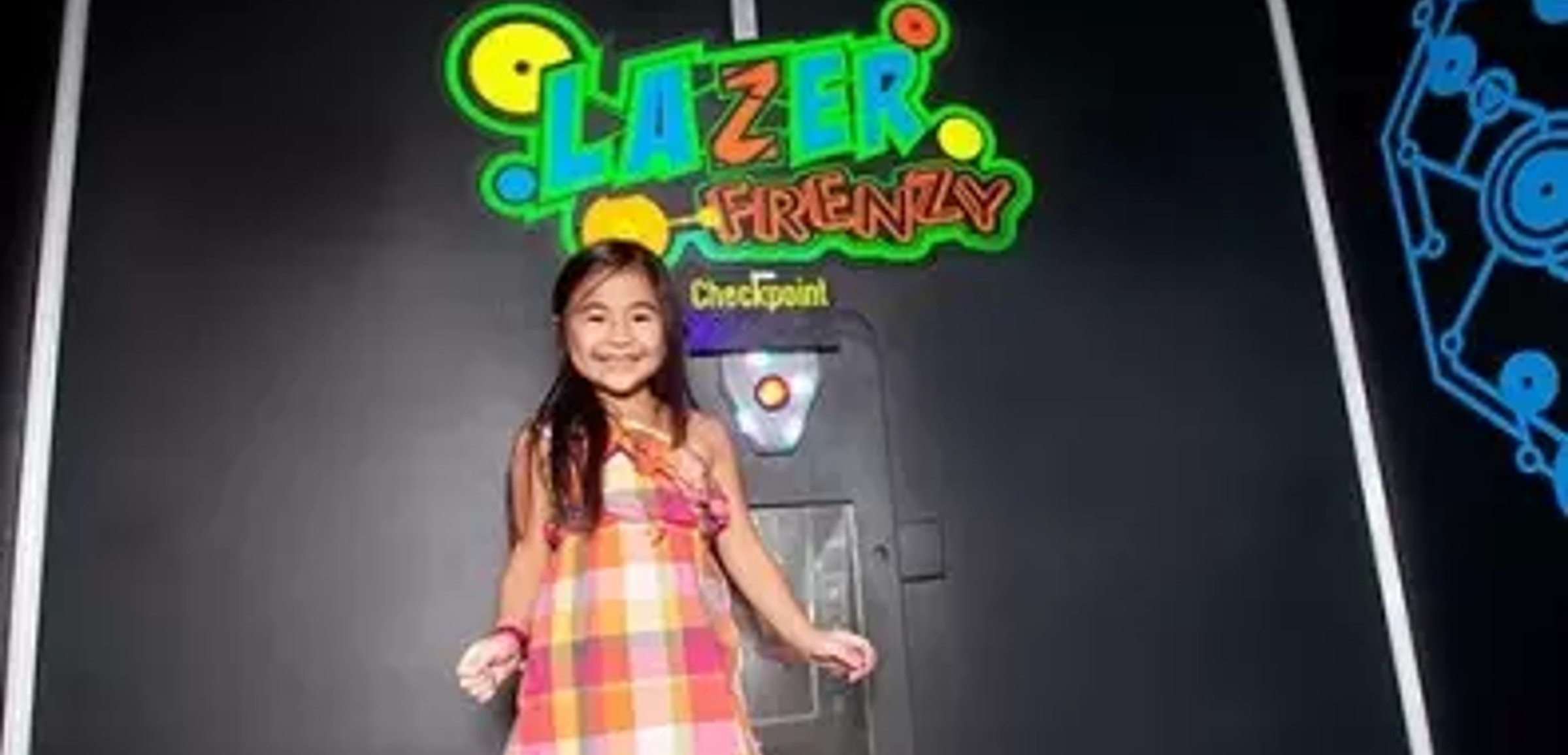A girl smiles at the entrance of Lazer Frenzy at Great Wolf Lodge indoor water park and resort.