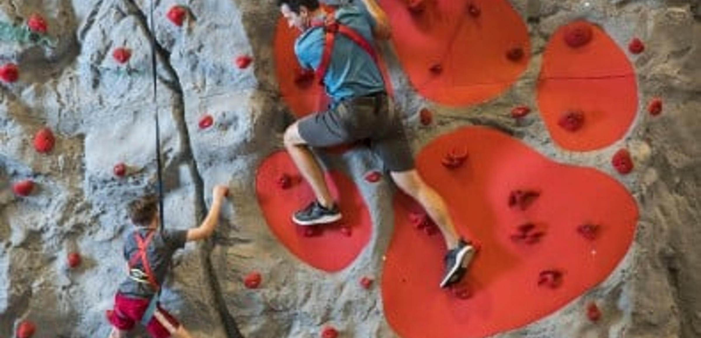 A family climbs a rock wall at Great Wolf Lodge indoor water park and resort.