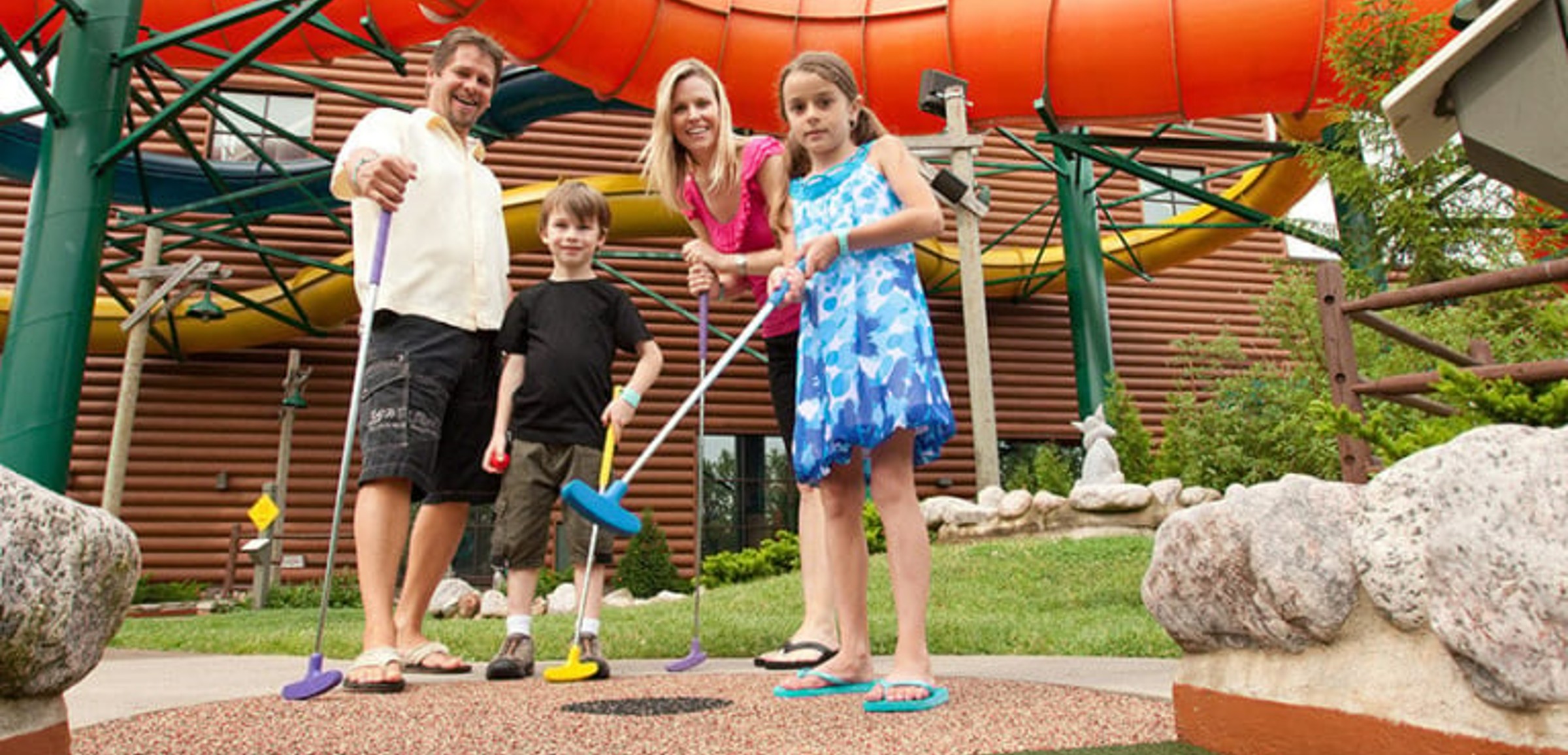 A family of four play indoor mini golf