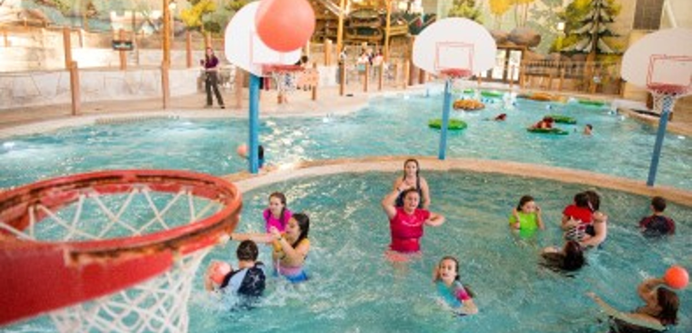 family playing basketball in indoor pool 