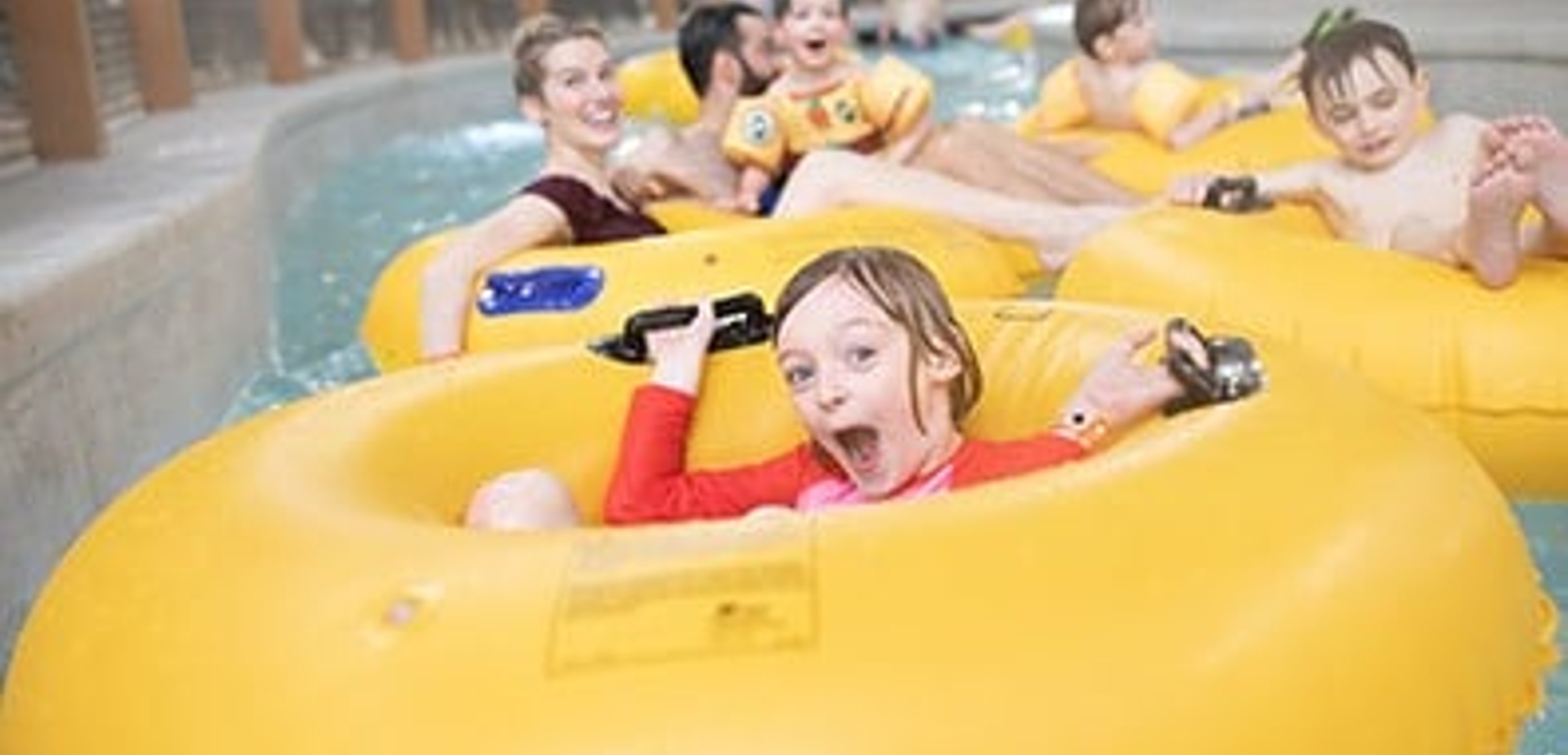 A girl float down the lazy river excitedly in her inner tube