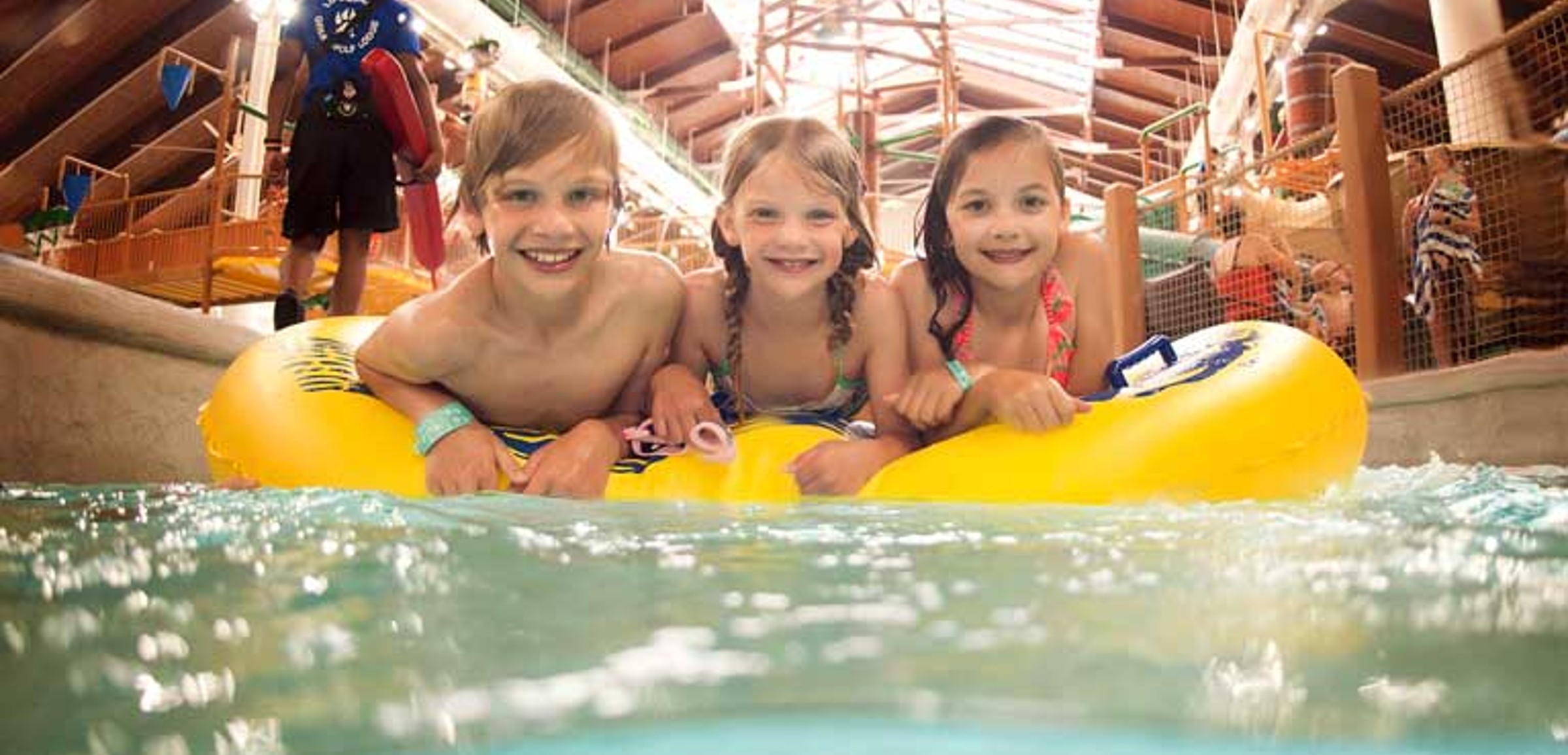 three smiling kids on a tube enjoying the lazy river