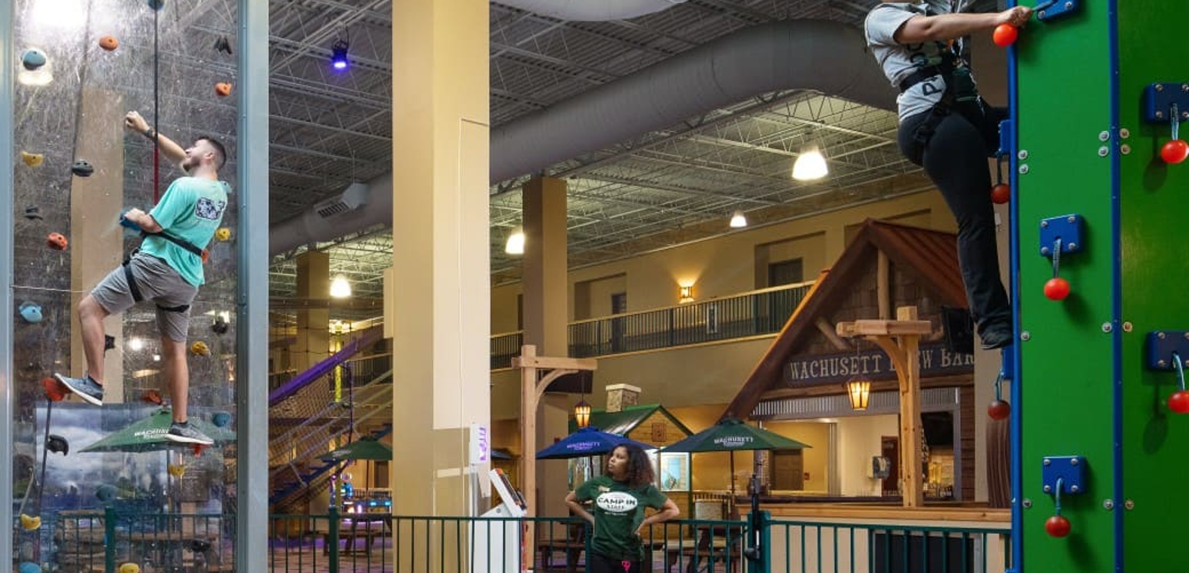 Family climbing an indoor rock wall with safety harnesses