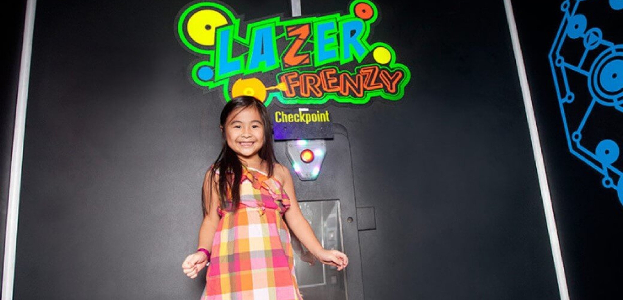 A girl smiles at the entrance of Lazer Frenzy at Great Wolf Lodge indoor water park and resort.