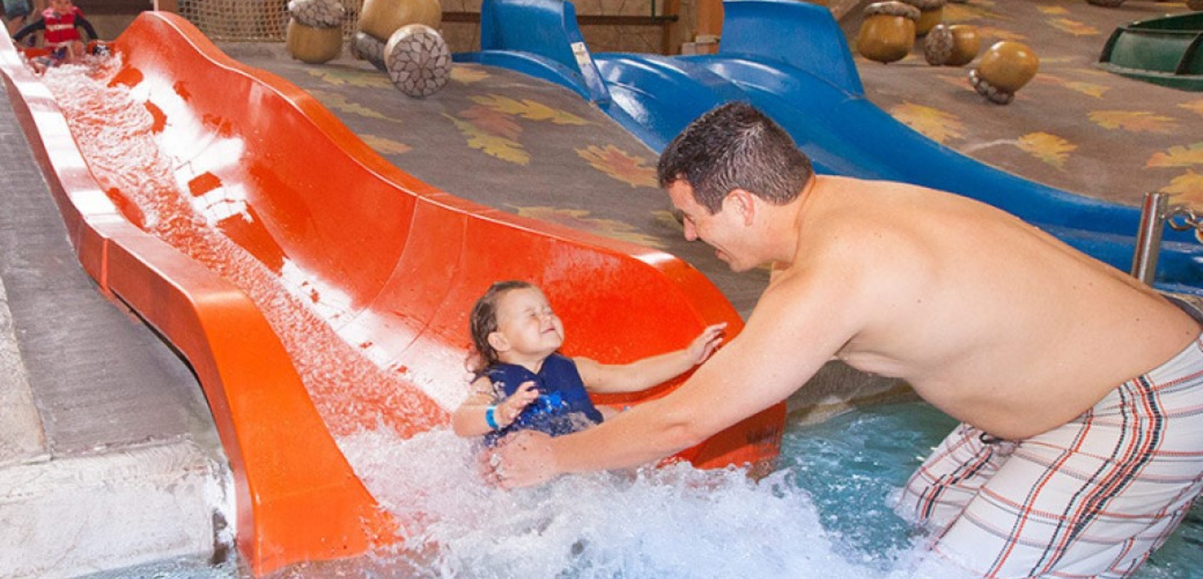 A small smiling child goes down the Kiddie Slides