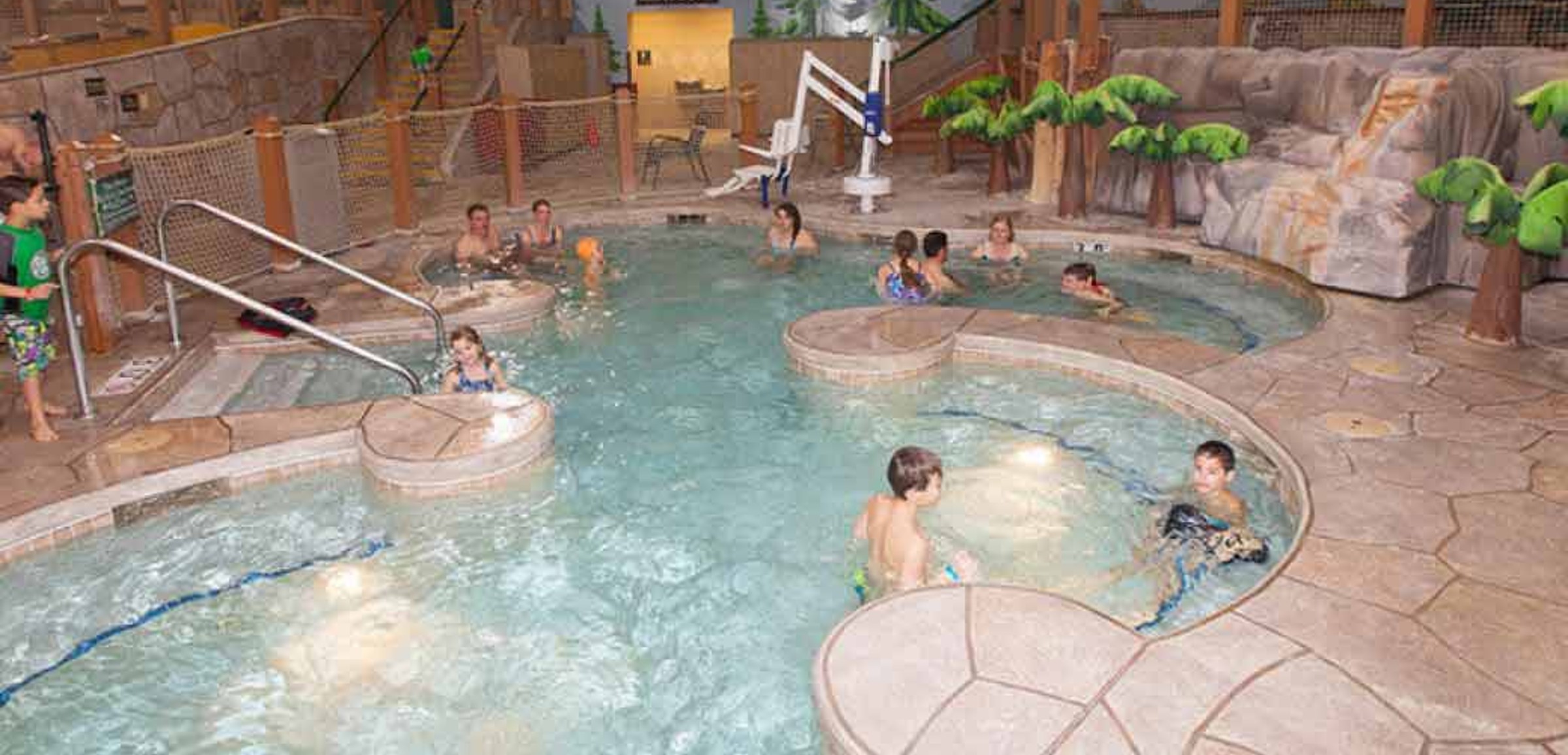 A couple relax in and on the side of the indoor pool 