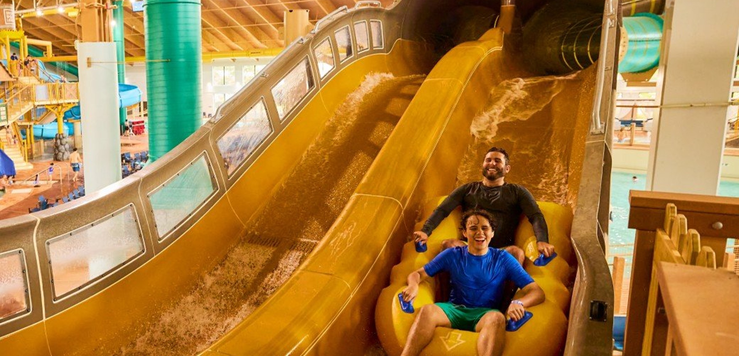 Boy rides down blue waterslide on yellow tube