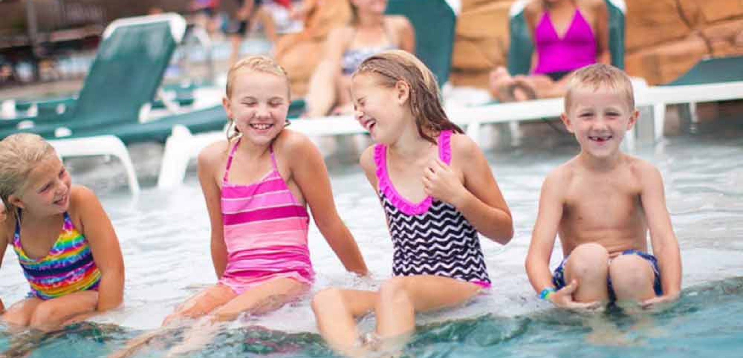 Four kidslaugh and  jump into outdoor pool