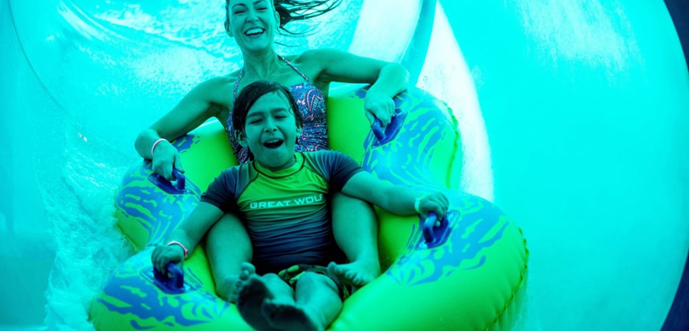 Mother and son in a tube racing down a yellow waterslide 