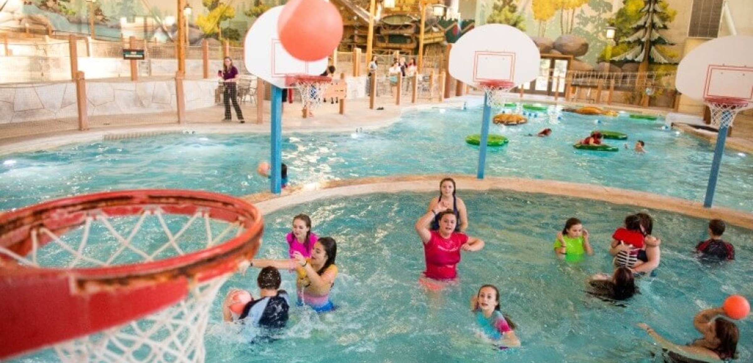 family playing basketball in indoor pool 