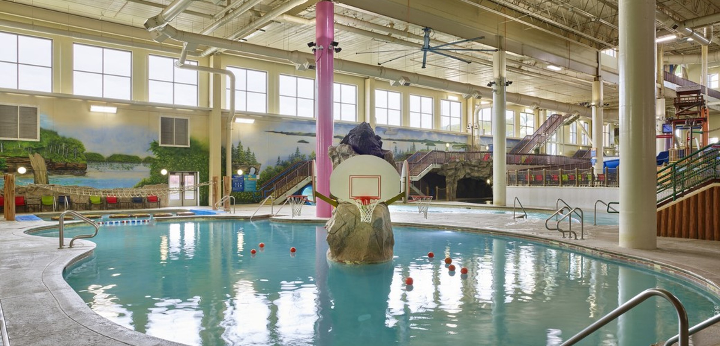 family playing basketball in indoor pool 