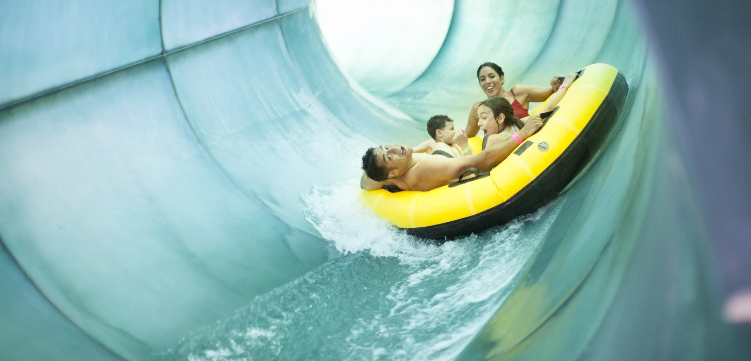 Family of four rides down waterslide in yellow tube