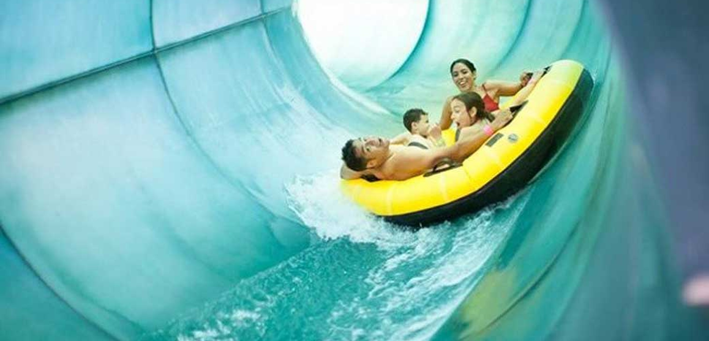 Family of four rides down waterslide in yellow tube