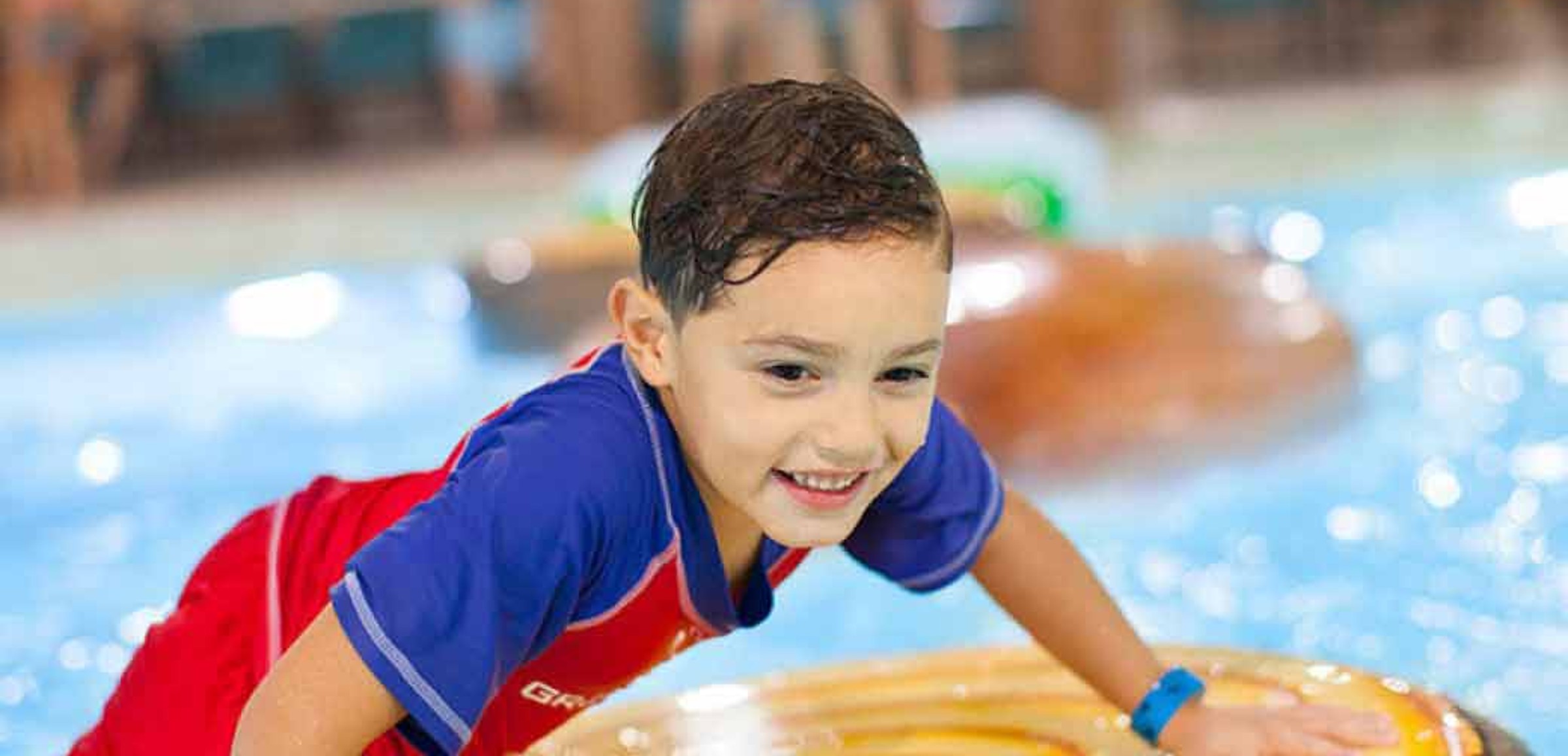 A boy balances himself on a float in the Frog Bog Log Walk pool at Great Wolf Lodge indoor water park and resort.