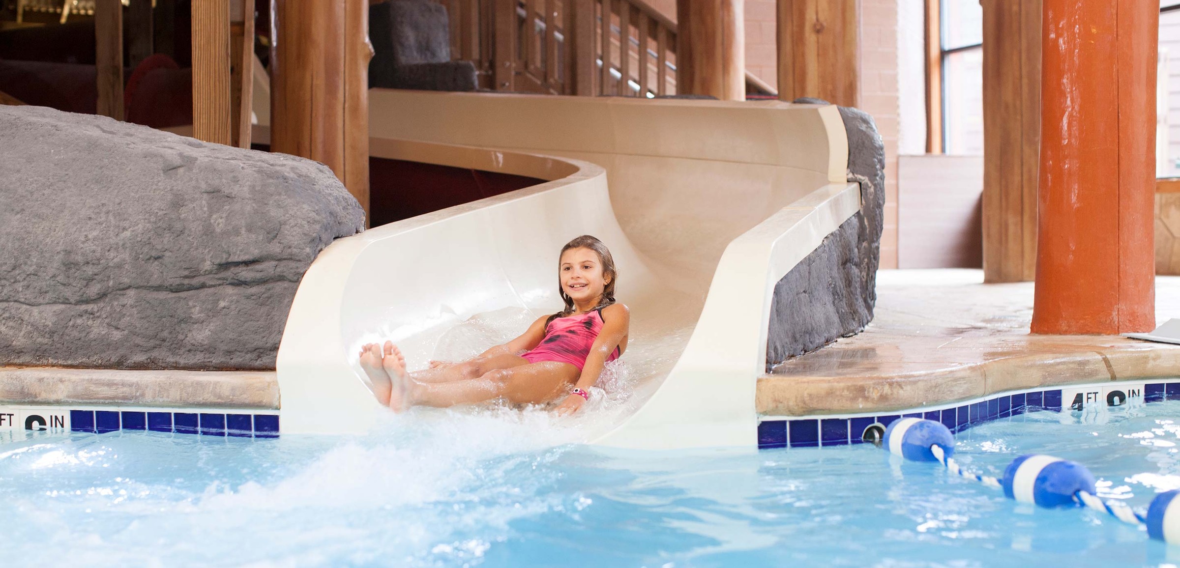 A girl riding down a water slide in a pink bathing suit.