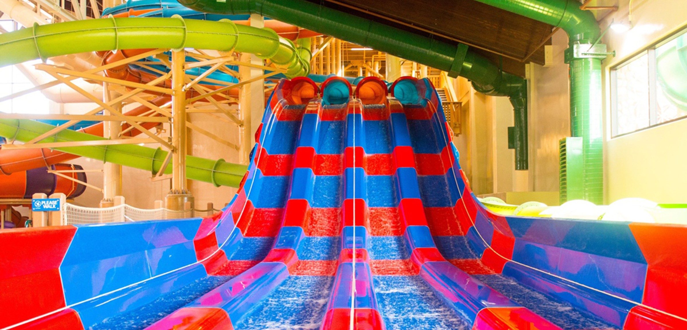 Two kids race down a waterslide laying on their stomaches 