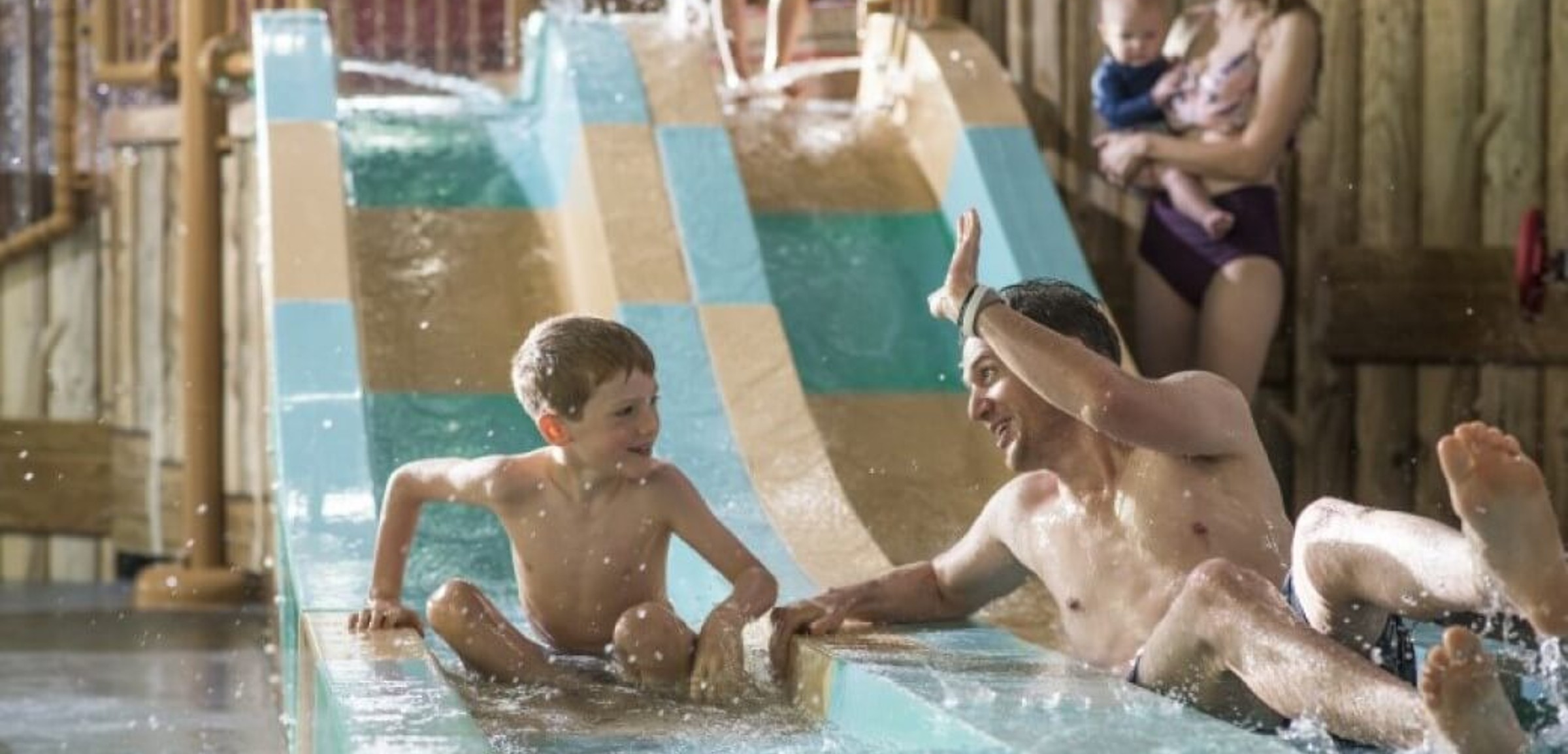 dad high fives his son as they come down a waterslide 