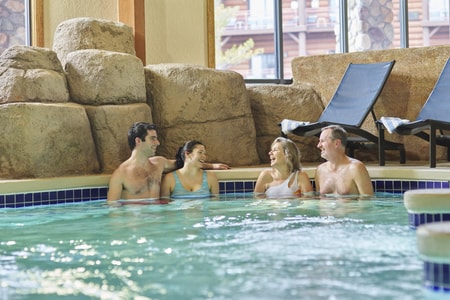 Two couples relax in an indoor hot tub