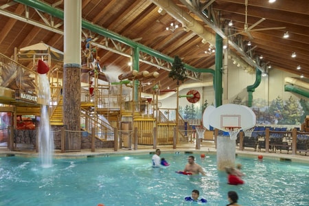family playing basketball in indoor pool 