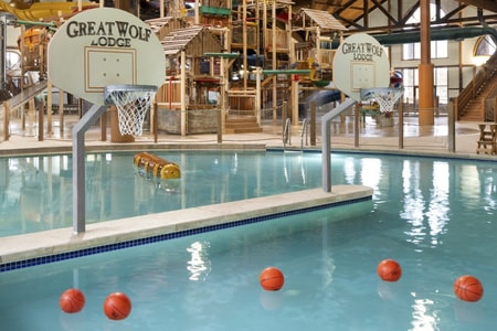 A large indoor water park featuring multiple slides and a basketball hoop for recreational activities.
